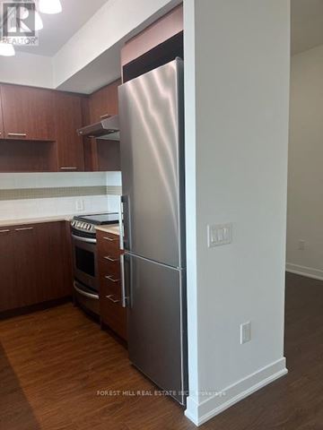 Toronto (Forest Hill South) house for rent - A stainless steel refrigerator stands in a kitchen with wooden cabinets.