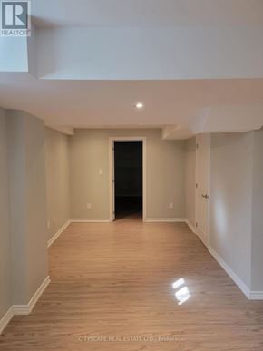Brampton (Fletcher's Creek South) apartment for rent - A spacious room with wooden flooring and white walls, with a black door at the end of the hallway.