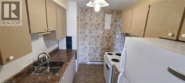 Guelph condo for rent - A kitchen with a sink, stove, and cabinets.