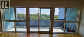 Guelph condo for rent - A balcony with a view of a forest and a fence.