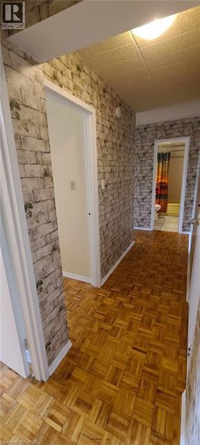 Guelph condo for rent - A hallway with a wooden floor and a brick wall.