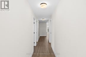 Brockville apartment for rent - A long hallway with white walls and wood flooring.