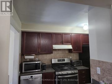 Vaughan (Maple) townhouse for rent - A kitchen with brown cabinets and a black stove top oven.
