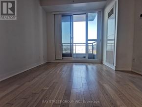 Richmond Hill (Langstaff) condo for rent - A spacious room with wooden flooring and a large window overlooking a balcony.