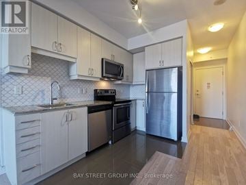 Richmond Hill (Langstaff) condo for rent - A kitchen with white cabinets and a black fridge.