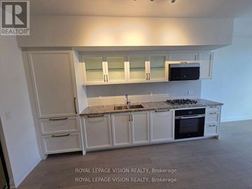 Toronto (Englemount-Lawrence) condo for rent - A kitchen with white cabinets and a granite countertop.