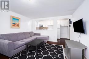 Toronto (East End-Danforth) duplex for rent - A living room with a grey couch and a painting of a beach scene on the wall.