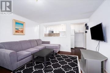 Toronto (East End-Danforth) duplex for rent - A living room with a grey couch and a painting of a beach scene on the wall.