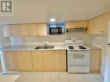 Toronto (Trinity-Bellwoods) apartment for rent - A kitchen with a white stove and cabinets.
