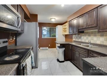 Surrey townhouse for rent - A kitchen with a stove top oven and a refrigerator.