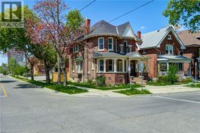Brantford apartment for rent - A large red brick house with a porch and a tree in front.