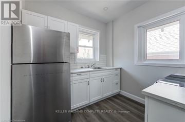 Brantford apartment for rent - A kitchen with a stainless steel refrigerator and white cabinets.