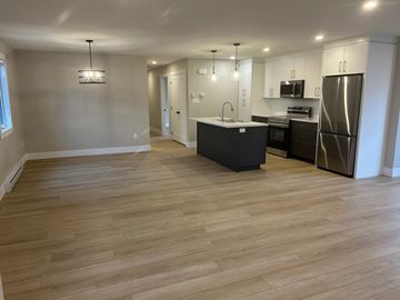 Shediac apartment for rent - A kitchen with a black island and stainless steel appliances.