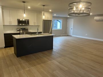 Shediac apartment for rent - A kitchen with a black island and wooden floors.