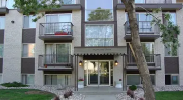 Edmonton apartment for rent - A modern apartment building with a balcony and a tree in front.