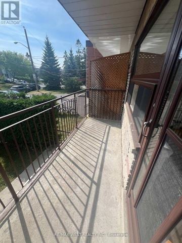 Toronto (Bathurst Manor) triplex for rent - A balcony with a metal railing and a view of a street and trees.