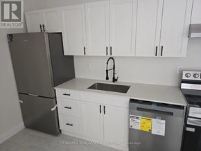 St. Catharines (E. Chester) apartment for rent - A kitchen with white cabinets and a black refrigerator.