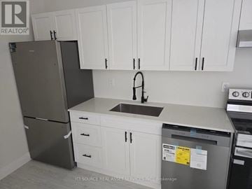 St. Catharines (E. Chester) apartment for rent - A kitchen with white cabinets and a black refrigerator.