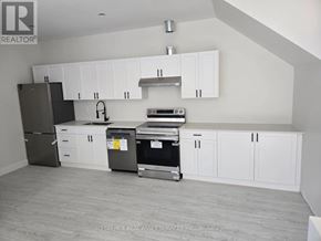 St. Catharines (E. Chester) apartment for rent - A kitchen with white cabinets and a black fridge.