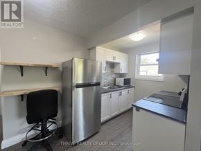 London South (South I) multi-family for rent - A kitchen with a stainless steel refrigerator, white cabinets, and a black chair.