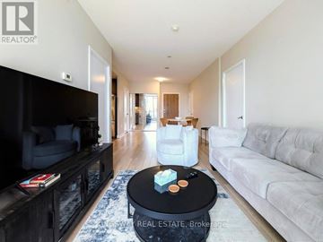 Mississauga (City Centre) condo for rent - A living room with a black coffee table in the middle of a white couch and a black entertainment center.