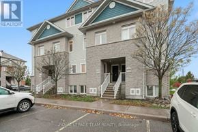 North Grenville townhouse for rent - A two-story building with a grey and blue exterior and a white car parked in front.