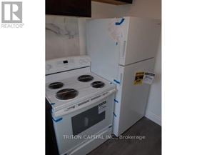 Hamilton (Dundas) apartment for rent - A white stove and refrigerator are taped off and in the process of being painted.