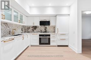 Toronto (Englemount-Lawrence) condo for rent - A white kitchen with a marble backsplash and a TV above the stove.