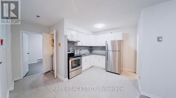 Toronto (South Parkdale) multi-family for rent - A kitchen with white cabinets and a stainless steel refrigerator.