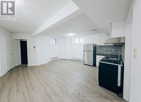 Toronto (South Parkdale) multi-family for rent - A spacious, empty room with a kitchenette and a dining area.