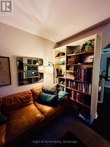 Oakville (Co Central) townhouse for rent - A living room with a brown leather couch and a bookshelf filled with books.