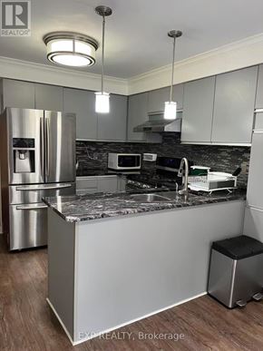 Pickering (Liverpool) apartment for rent - A kitchen with a refrigerator, microwave, and a countertop.