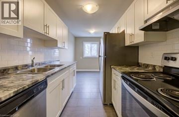 London apartment for rent - A kitchen with white cabinets and a black stove top.