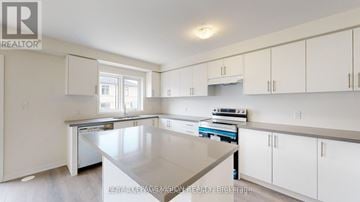 Oshawa (Eastdale) townhouse for rent - A kitchen with white cabinets and a large island.