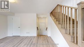 Oshawa (Eastdale) townhouse for rent - A spacious room with a staircase leading to the upper floor.