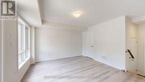 Oshawa (Eastdale) townhouse for rent - A spacious, empty room with a door on the right and a window on the left.