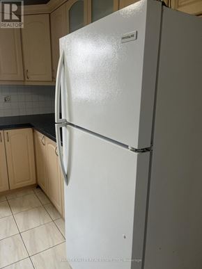 Toronto (Dovercourt-Wallace Emerson-Junction) apartment for rent - A white fridge in a kitchen with wooden cabinets.