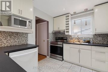 Niagara Falls (Oldfield) apartment for rent - A kitchen with white cabinets and a black countertop.