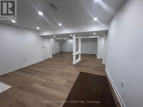 Clarington (Bowmanville) apartment for rent - A spacious room with wooden flooring and white walls, with a brown rug on the floor.