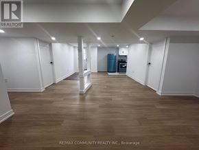 Clarington (Bowmanville) apartment for rent - A spacious room with wooden flooring and white walls, furnished with a kitchenette.