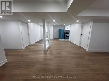 Clarington (Bowmanville) apartment for rent - A spacious room with wooden flooring and white walls, furnished with a kitchenette.