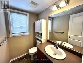 Ottawa townhouse for rent - A bathroom with a toilet, sink, and medicine cabinet.