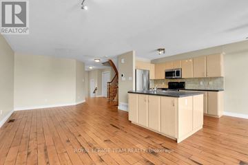 Ottawa townhouse for rent - A room with wooden floors and a kitchen area with cabinets and a countertop.
