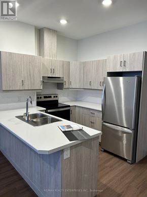 Owen Sound condo for rent - A modern kitchen with a stainless steel refrigerator and wooden cabinets.