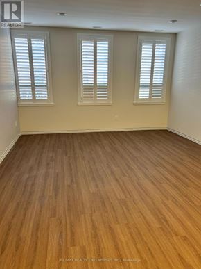Owen Sound condo for rent - A room with wooden flooring and three windows.