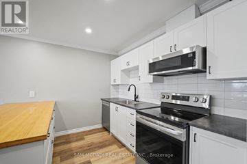 Clarington (Bowmanville) apartment for rent - A kitchen with white cabinets and a black stove top oven.