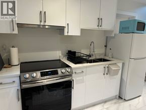 Vancouver apartment for rent - A modern kitchen with white cabinets and a black stove top oven.