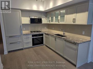 Toronto (Englemount-Lawrence) condo for rent - A kitchen with white cabinets and a granite countertop.