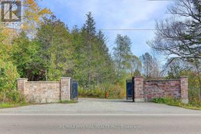 Whitchurch-Stouffville apartment for rent - A gate with a brick wall and a metal gate in front of a forest.