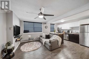 Niagara Falls (Downtown) multi-family for rent - A living room with a grey couch and a ceiling fan.